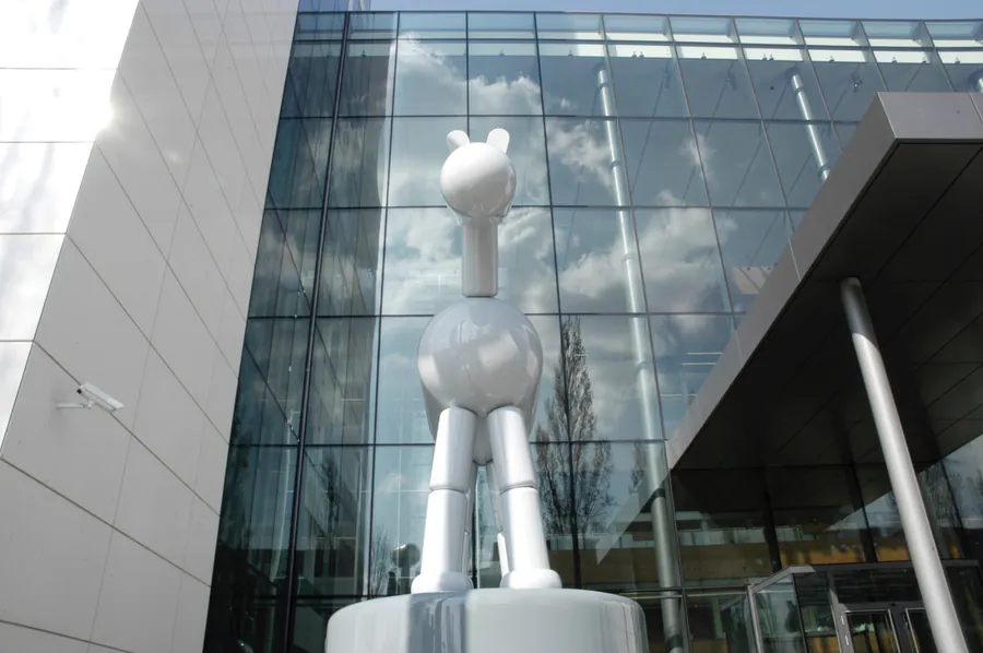 Kunst am Bau - hochglanzweiße Skulptur vor einer Glasfassade, realisiert von der hertzer GmbH
